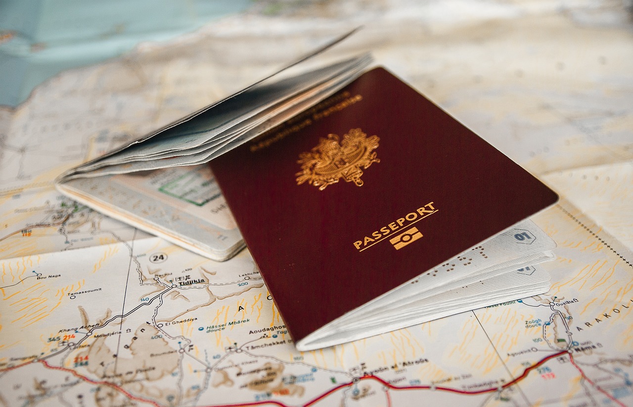 Dwa czerwone paszporty, leżące na rozłożonej papierowej mapie świata