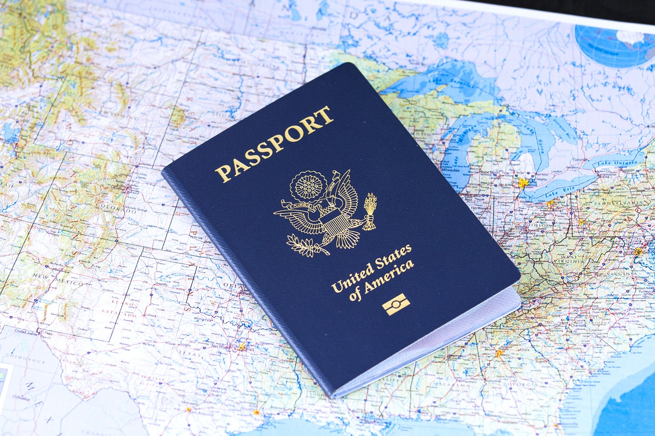 Niebieski paszport obywatela Stanów Zjednoczonych leżący na rozłożonej papierowej mapie świata