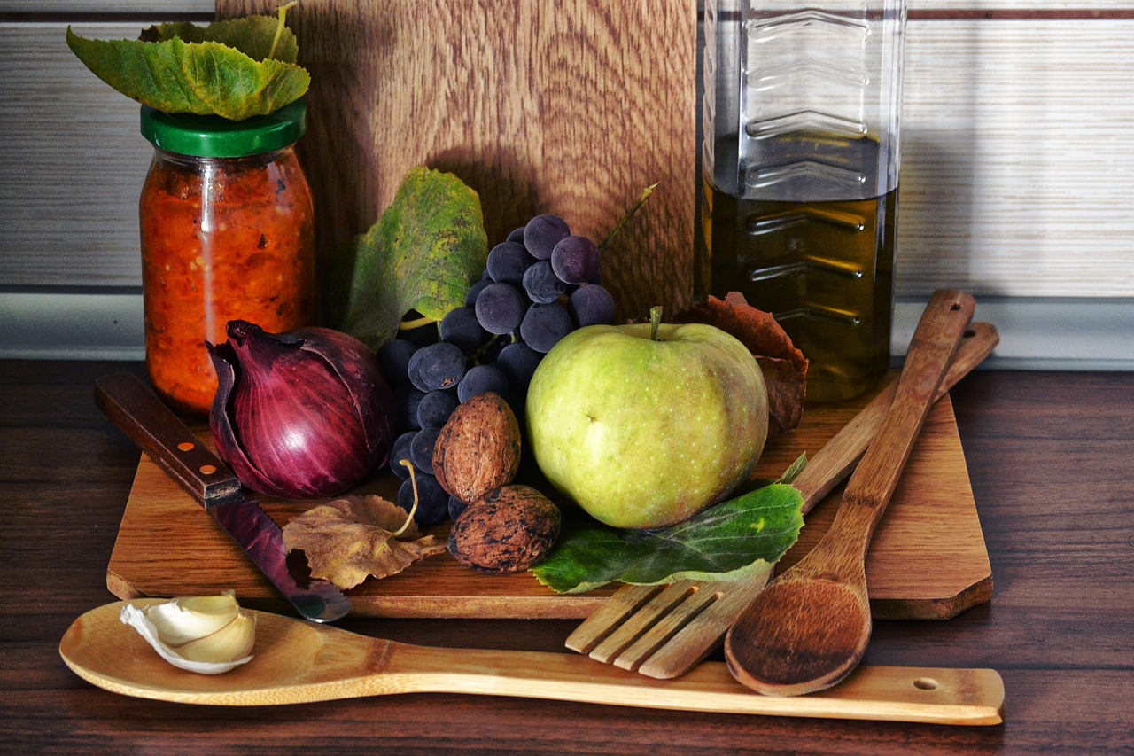 Oliwa, czosnek oraz inne warzywa i owoce na drewnianej desce na blacie w kuchni